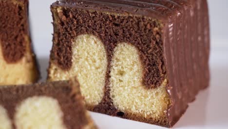 a reveal shot of a baked marble cake loaf with chocolate icing and a few slices