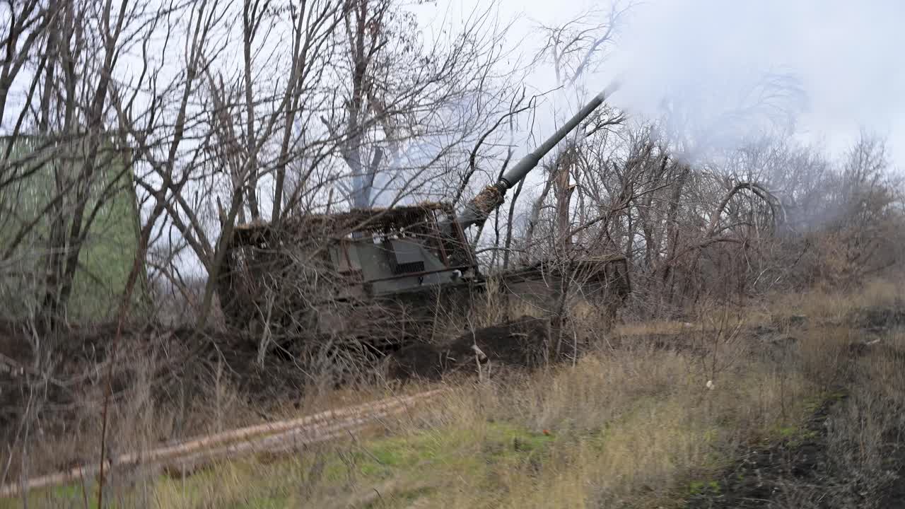 A Ukrainian PzH 2000 self-propelled howitzer fires its 155mm cannon from a concealed position. Smoke billows from the muzzle as it sends a shell towards Russian targets