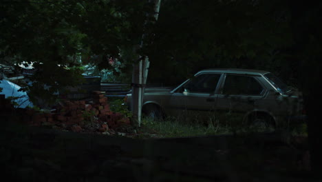 old car surrounded by trees and demolition waste