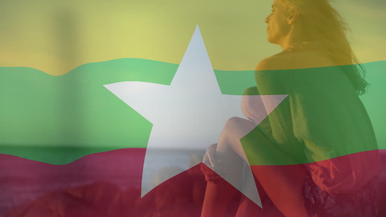 Sitting by ocean, person relaxing with Myanmar flag animation overlaying scene