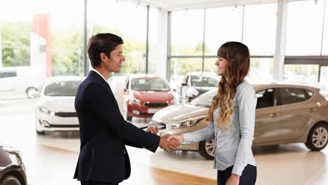 caucasian male and female shaking hands in a car distributor