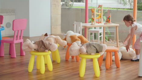 happy cheerful little girl playing with cuddly plush bears