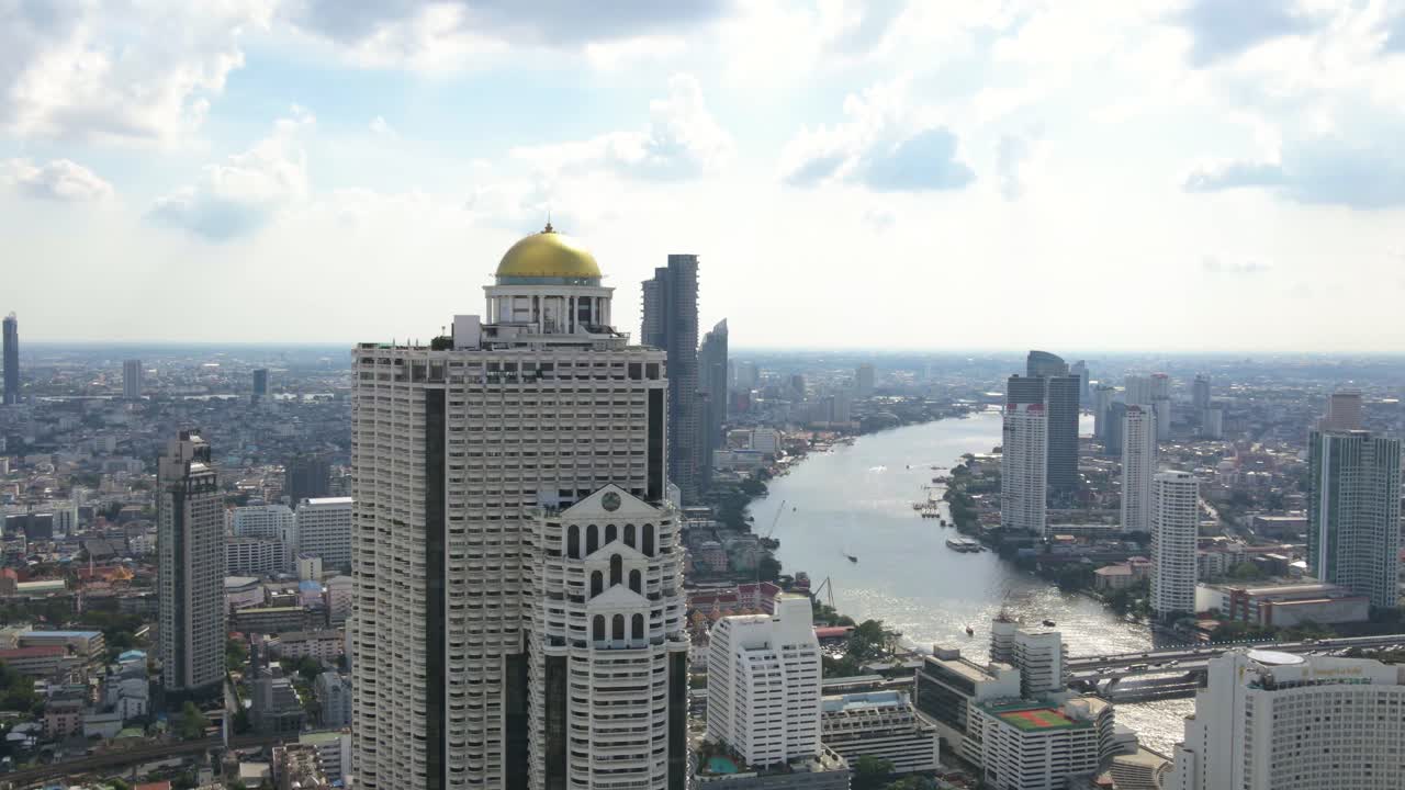 Aerial view of the iconic Lebua Hotel in Bangkok with panoramic Chao Phraya River backdrop on a clear day