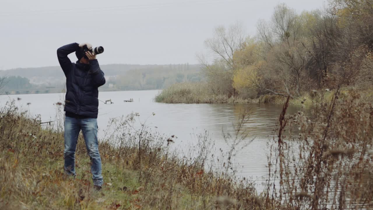 Man taking photo of landscape. Aerial view of man photographer taking photo on lake shore