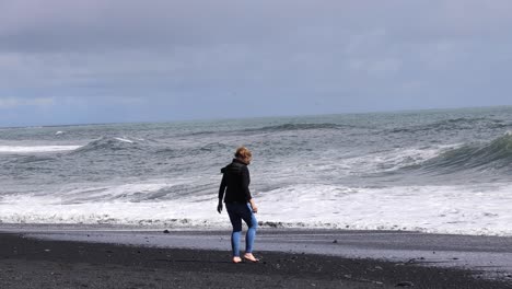 Frau-Am-Schwarzen-Strand-Steine-Aufheben