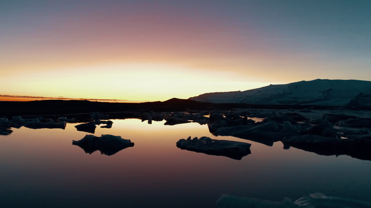 playa de diamantes, vista aérea de la puesta de sol brillante de islandia sobre la playa de arena negra con enormes fragmentos de iceberg relucientes