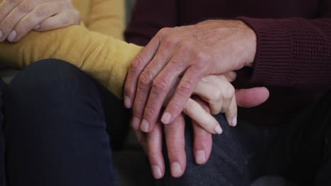 mid section of senior caucasian couple sitting and holding hands