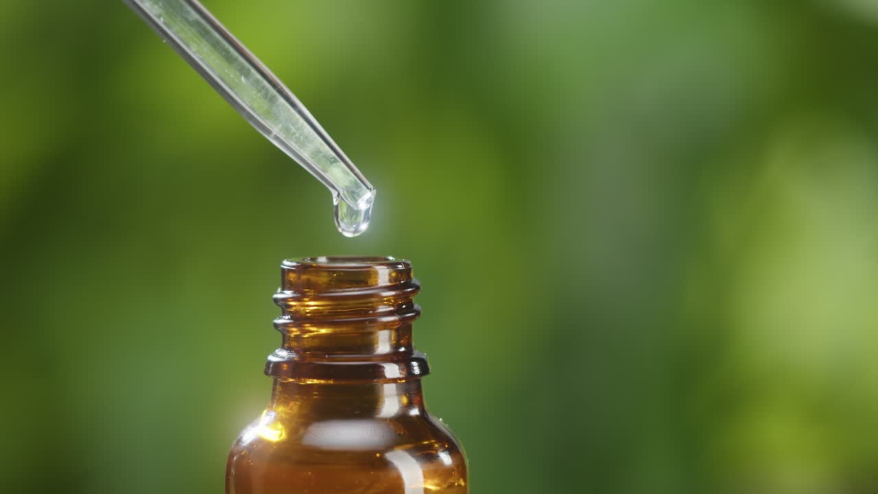goteo de aceite de pipeta en botella de primer plano, jugo de planta. hacer suero de aroma en fondo verde. goteo de extracto líquido, rutina de cuidado de la piel, aceite esencial de tratamiento, concepto de spa. medicina tradicional