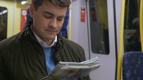 Pendler-Verbringt-Zeit-Mit-Zeitung-In-Der-U-Bahn