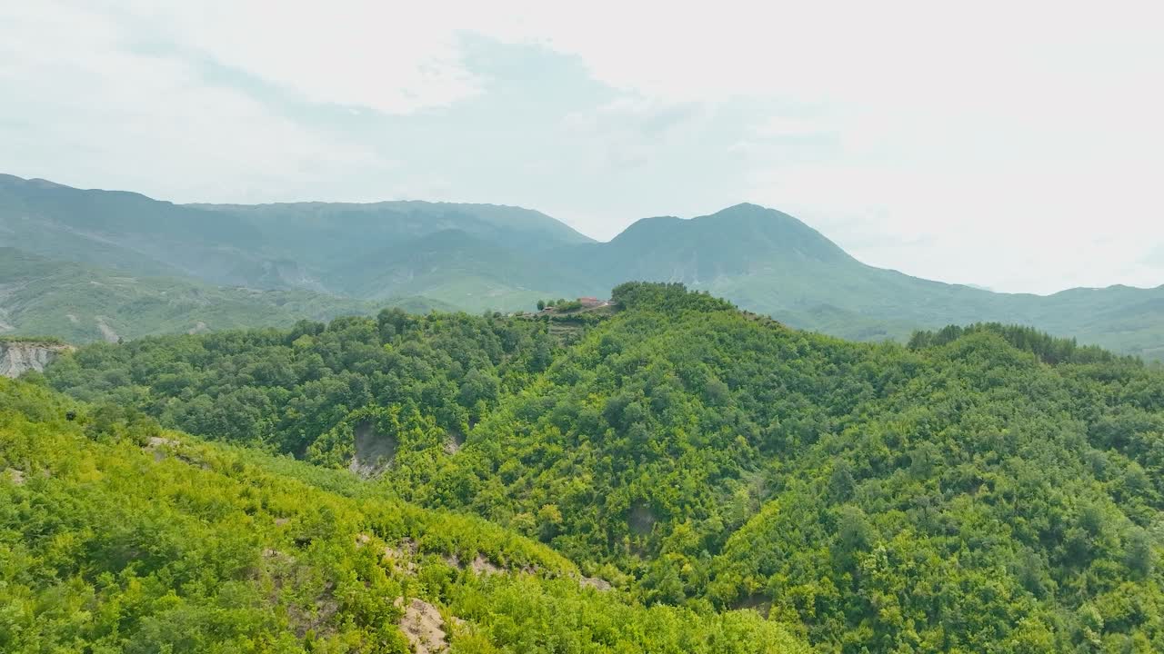 숲과 작은 집들이 위에 있는 지중해 언덕 꼭대기의 총면적