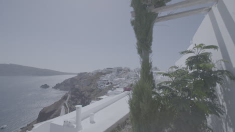 visión general de santorini grecia en un día soleado visto desde una terraza con plantas en frente en cámara lenta y el mar en el fondo que refleja el registro del sol