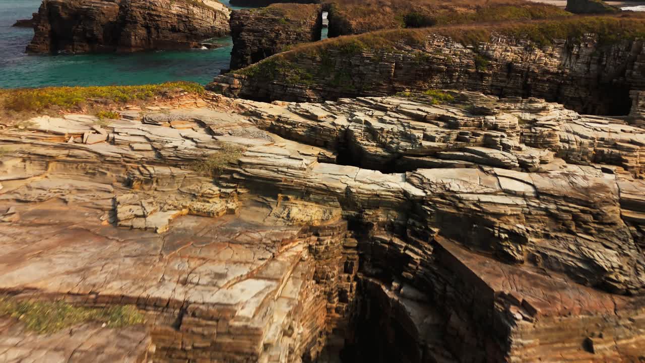 Drone fly-away shot over turquoise waters revealing dramatic sea cliffs and a narrow rock passage