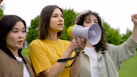 three female friends in a protest using a megaphone