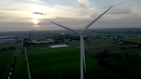 Static-shot-of-spinning-windmill-blades-agains-a-setting-sun