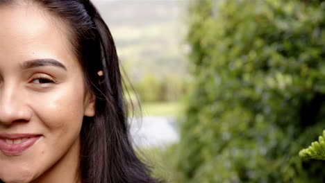 A-young-biracial-woman-smiles-in-the-backyard-at-home,-half-her-face-visible,-copy-space