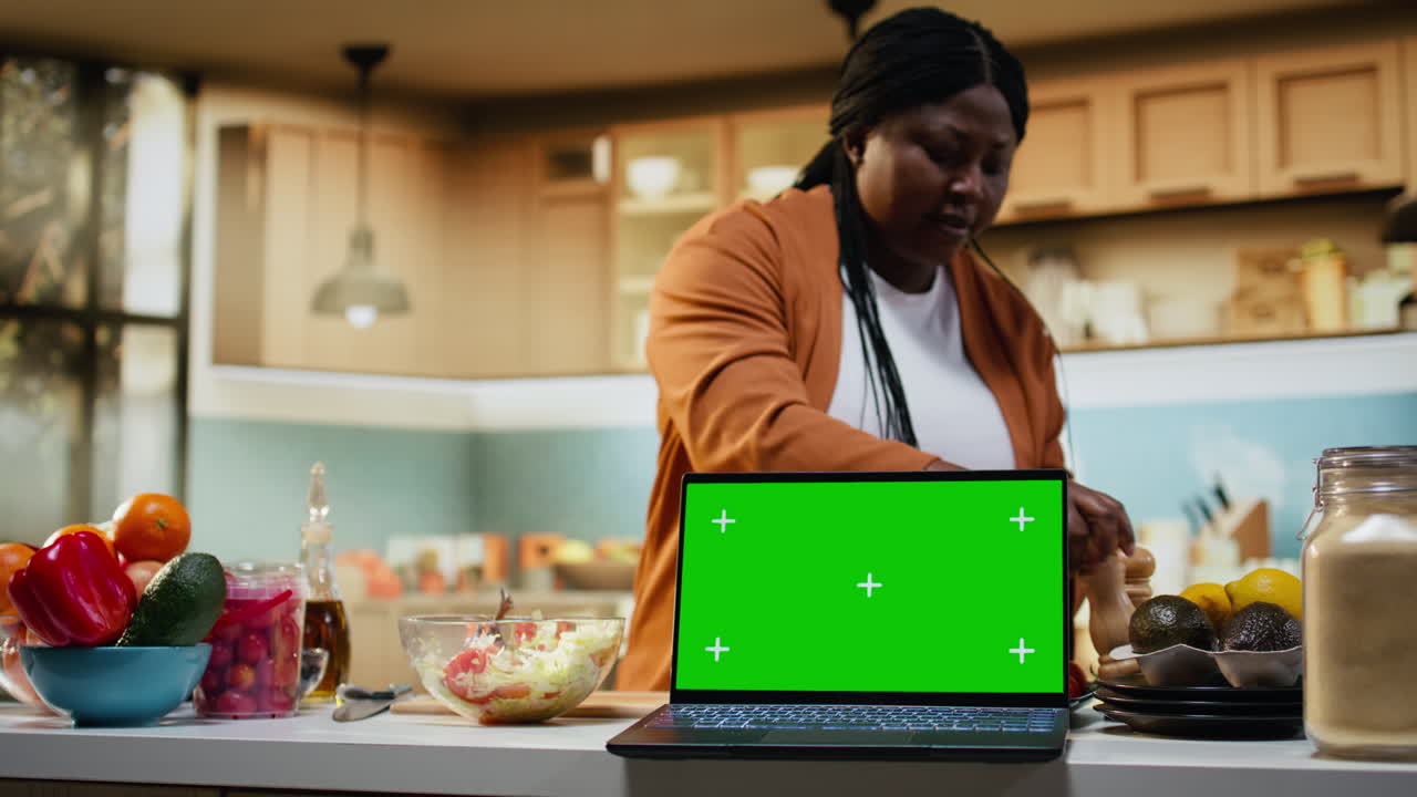 Layar maket di laptop dengan wanita Afrika-Amerika sedang mempersiapkan makanan