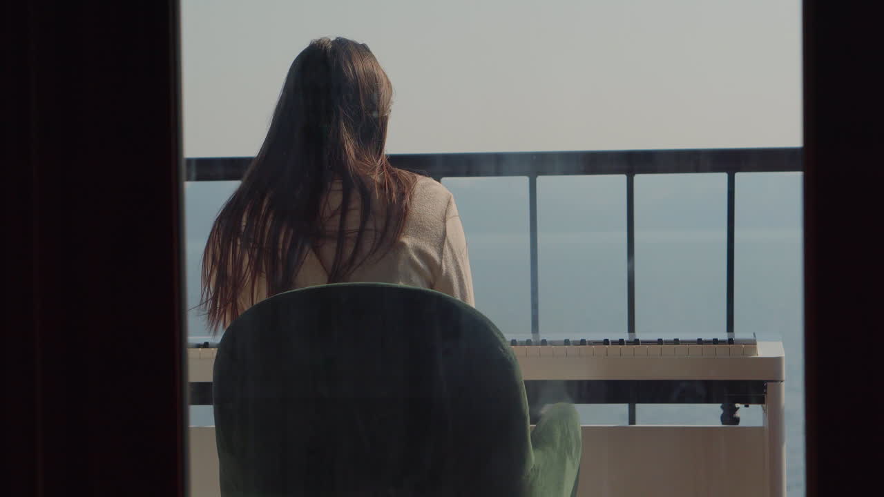 Woman playing piano on a balcony overlooking the sea