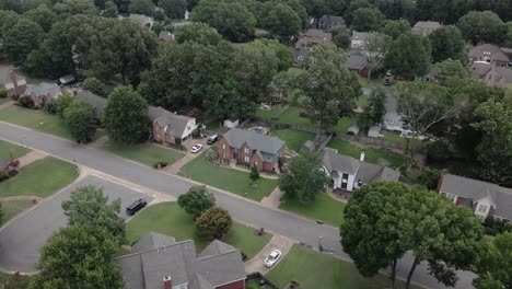 A drone zoom-in shot capturing a suburban neighborhood in the United States, showcasing tree-lined streets and residential houses. The greenery and -planned layout highlight the peaceful.