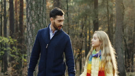 caucasian happy father and his daughter walking and talking in the forest