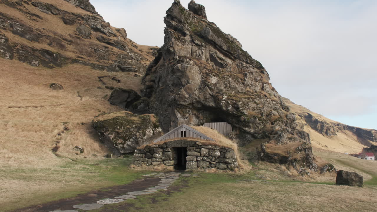 Rútshellir, a traditional Icelandic turf house built into the rugged hillside beneath a towering rock formation