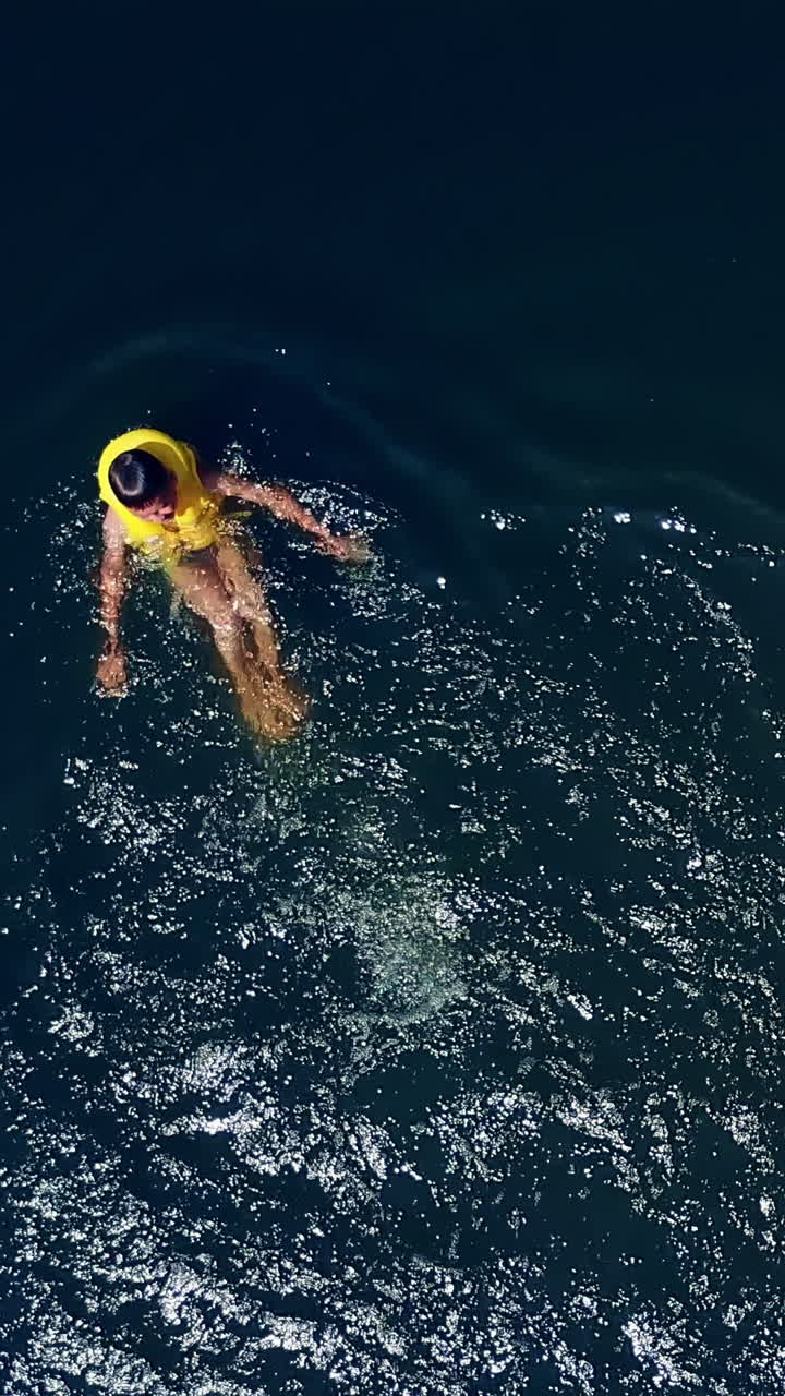 The guy is swimming in the river. Happy children on summer vacation. Aerial view Vertical video