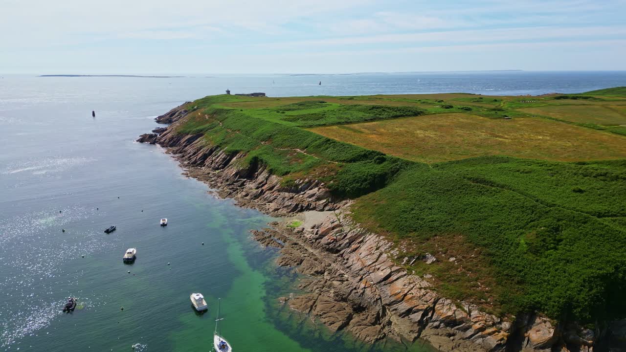 Flying over green Kermorvan Peninsula towards historic lighthouse, rugged coastline and calm Atlantic Ocean on sunny day in Brittany, France. Aerial drone sideways