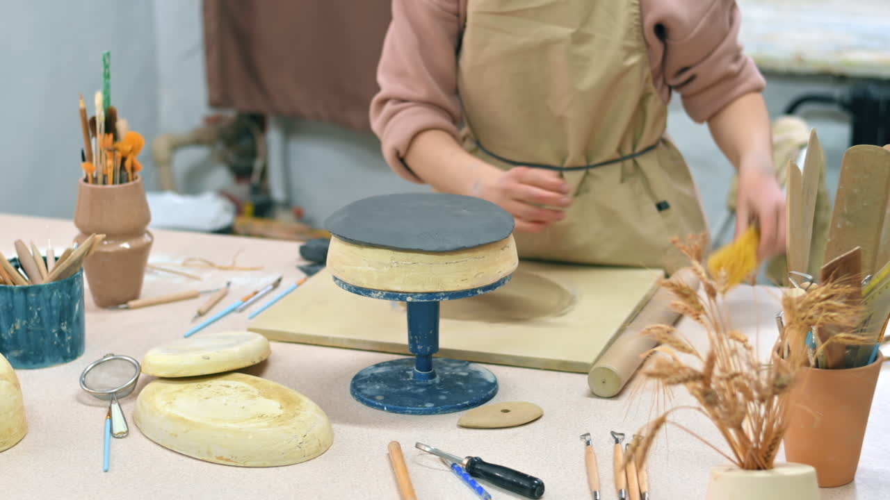 The master of sculpting pottery working in a studio. Giving a rounded shape to the clay. Tools and materials on the table