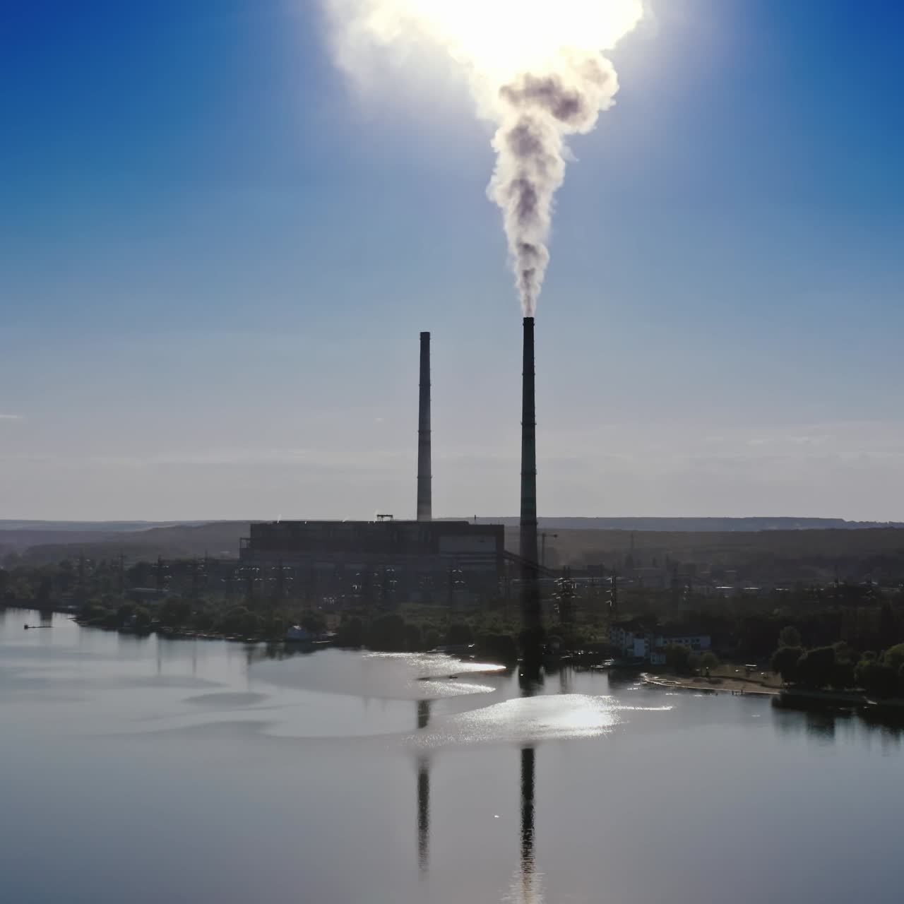 Smokestack in factory with blue cloudless sky. Sunset above modern factory. Panoramic video with drone