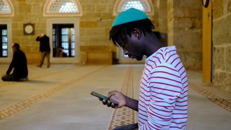 Black-man-texting-message-in-mosque
