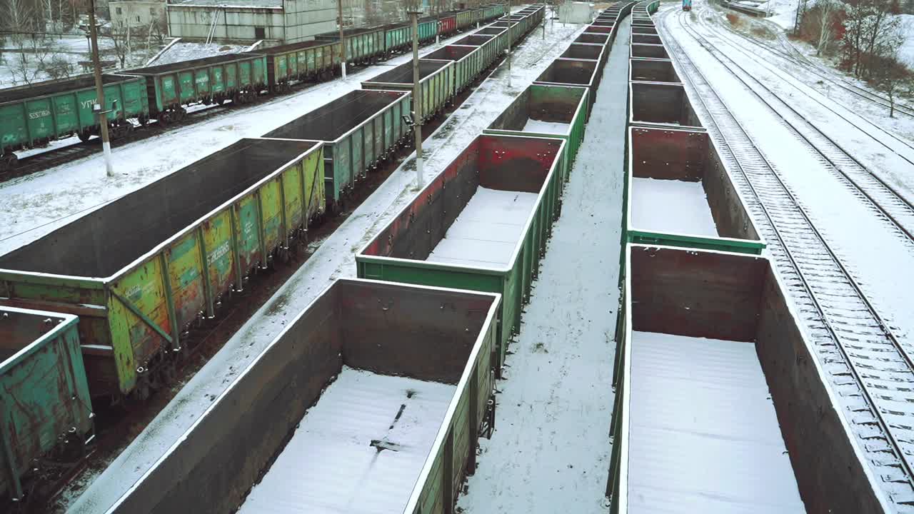 View of the rows with empty containers for the supply of goods, sprinkled with snow on the background of the railway station outside the city. Logistics.