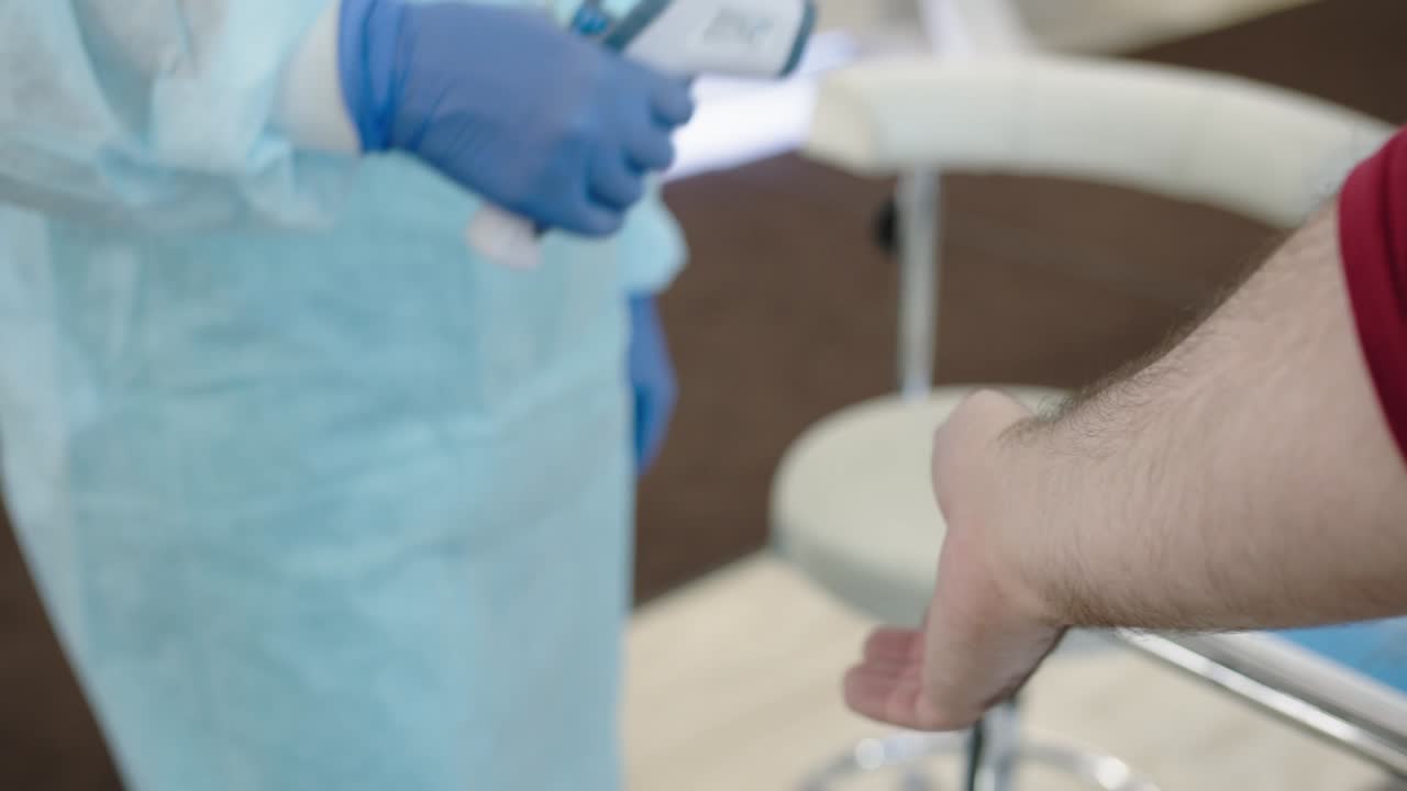 Checking the temperature with a non-contact thermometer. A nurse in gloves checks body temperature using a remote measuring device to detect coronovirus infection in the early stages