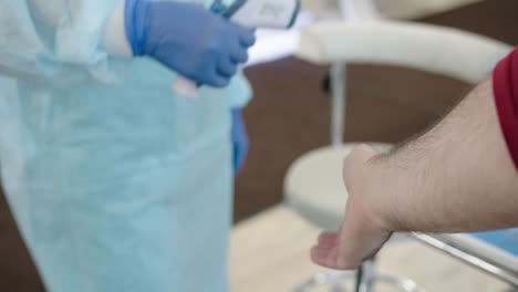 checking the temperature with a non-contact thermometer. a nurse in gloves checks body temperature using a remote measuring device to detect coronovirus infection in the early stages