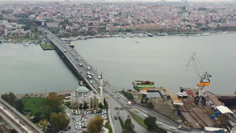 aerial view of cars and busses crossing ataturk bridge over the bosphorus river next to a mosque on a cloudy morning in istanbul turkey