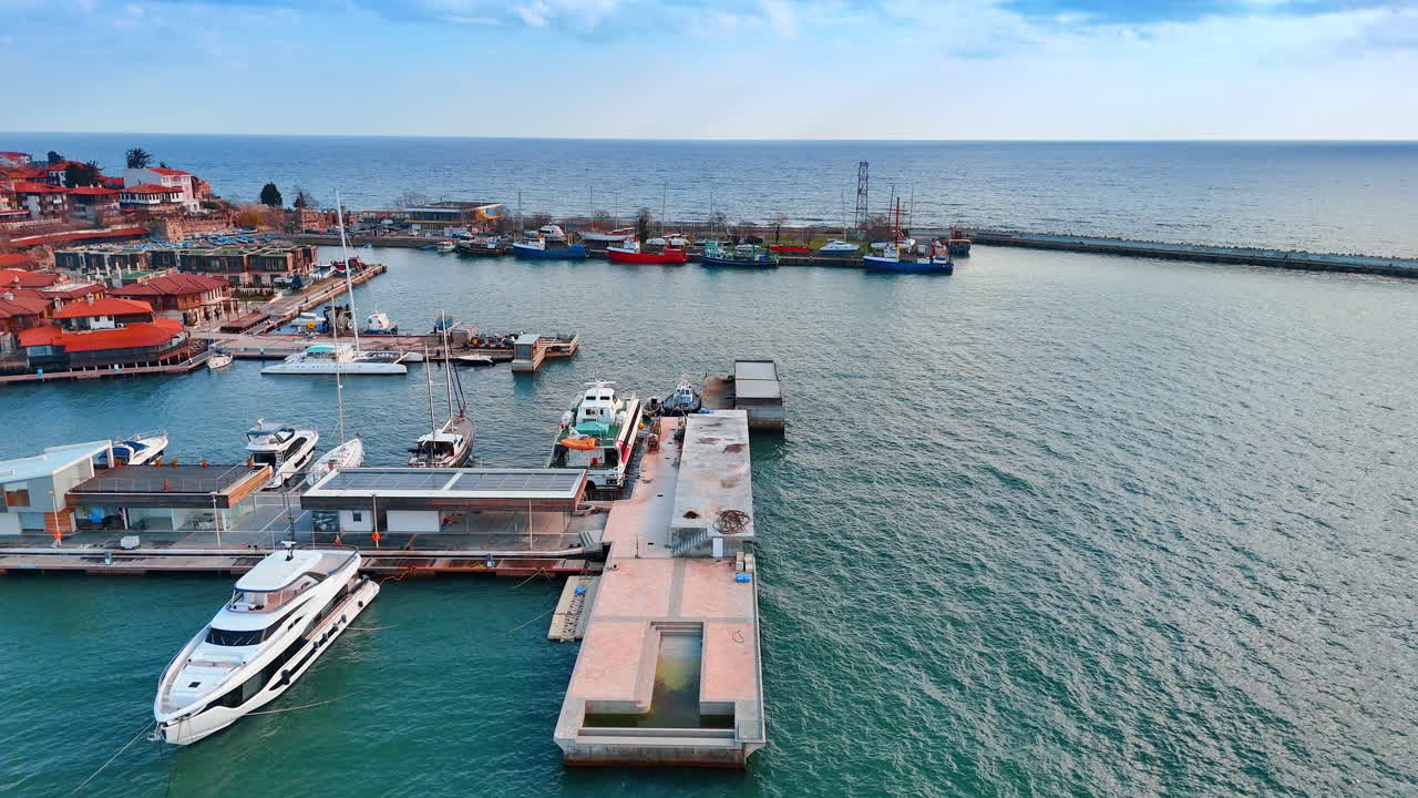 Veduta aerea di uno yacht bianco di lusso al molo del porto. Yacht bianco ormeggiato a un molo con pannelli solari in un porto marittimo durante il giorno.