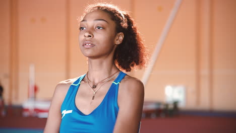 portrait of a young sportswoman warming up and stretching arms in an indoor sport facility