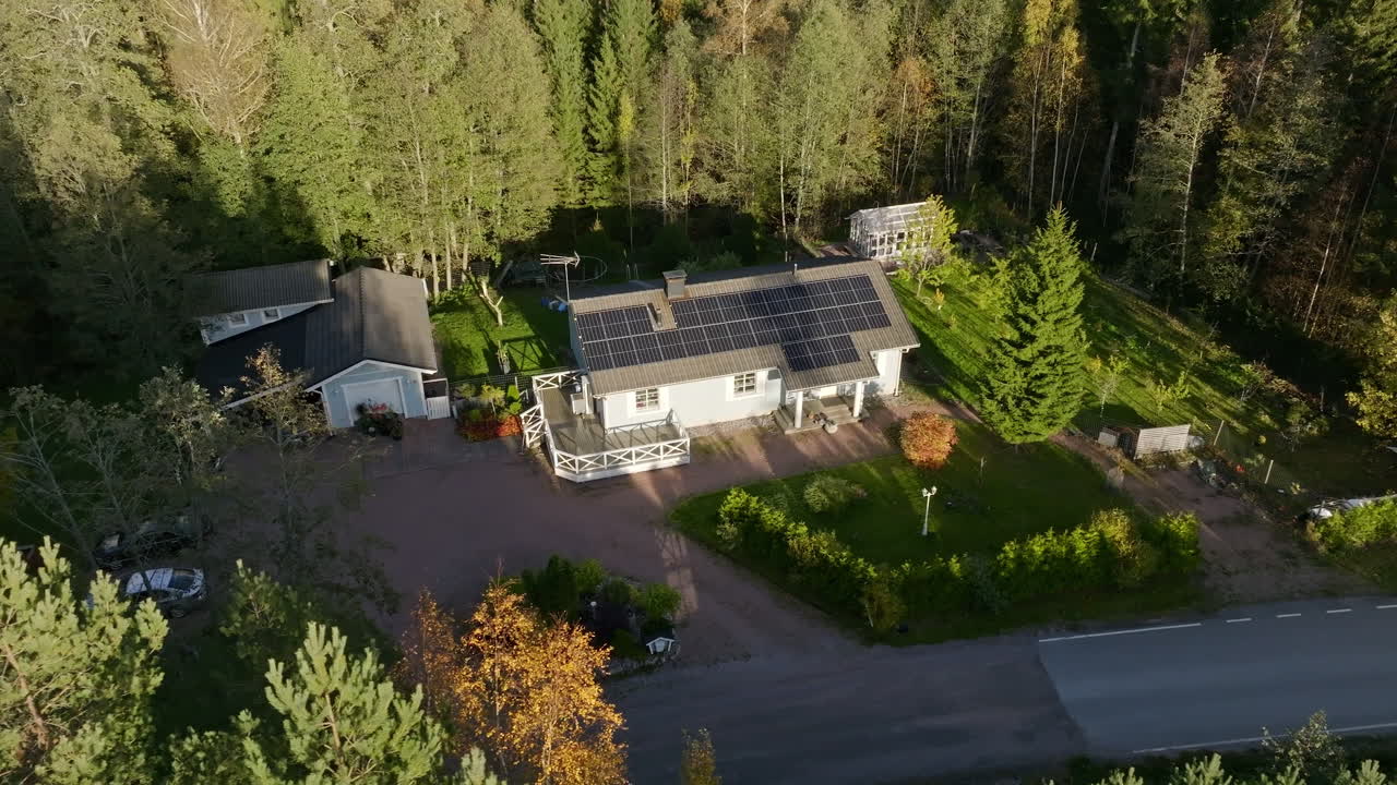 Drone circling in front of a solar house in middle of sunlit autumn color forest
