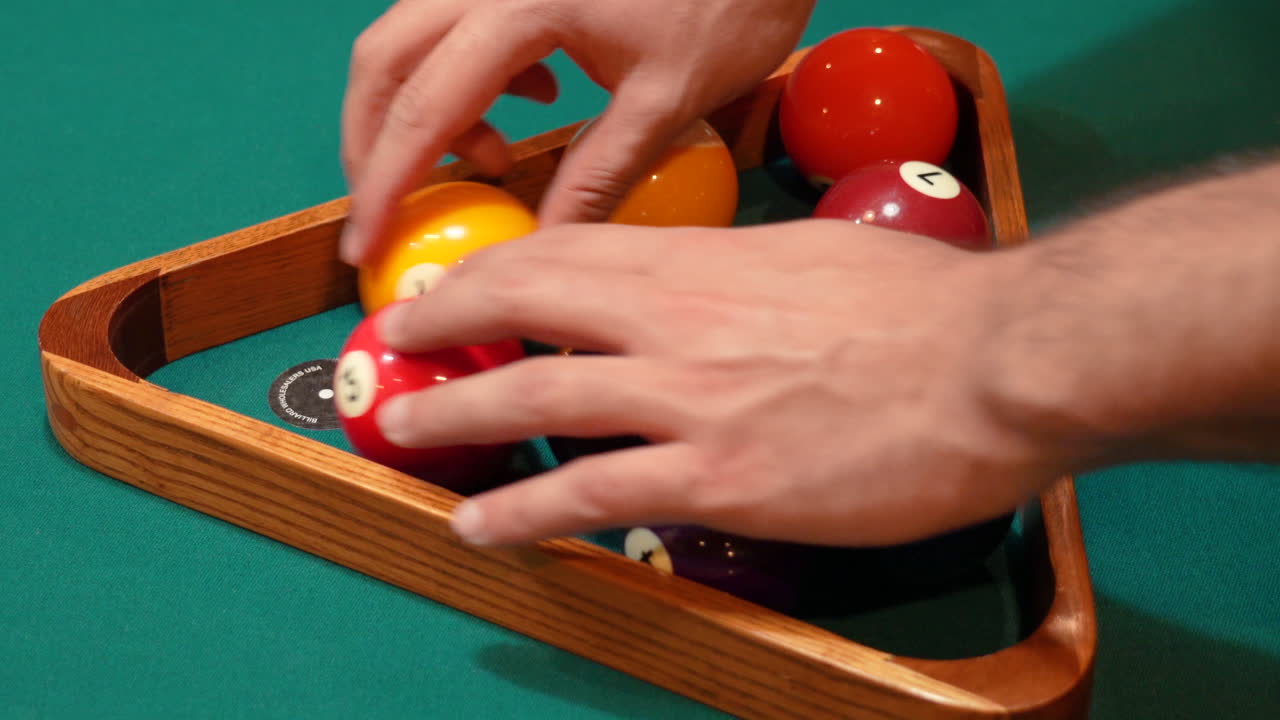 Person Racks 9 Ball Pool Diamond Closeup on the Spot and Arranges Solid and Striped Billiard Balls on Table with Green Felt or Cloth and Tightening Rack with Hands before Lifting Wooden Triangle