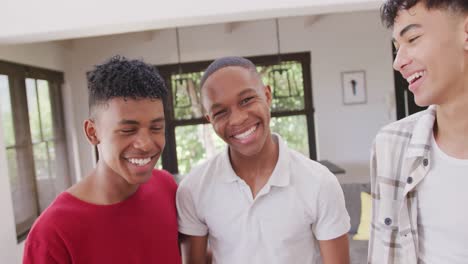 portrait of happy diverse male teenage friends embracing at home, slow motion