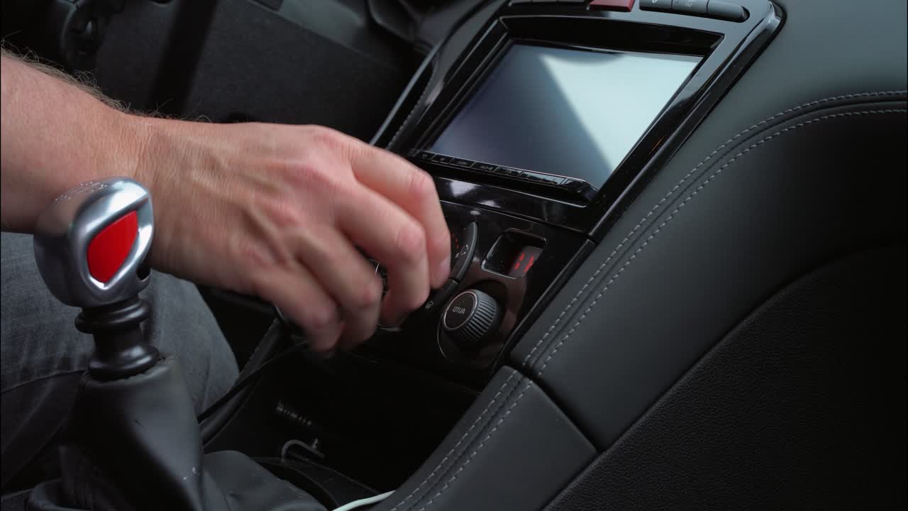 Car air conditioning being turned up by male hand left hand drive stick shift