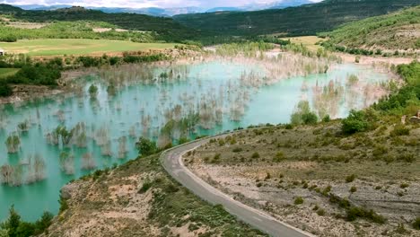 camión moviéndose a lo largo de la carretera curva junto a la cubierta montañosa de españa cubierta de agua, drones que cubren el flujo de agua a lo largo de las crestas de españa