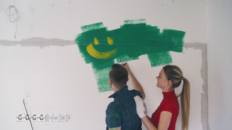 man-draws-smiling-face-with-yellow-at-wife-in-modern-flat