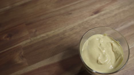 medium close shot of yellow mustard sitting in a small glass jar