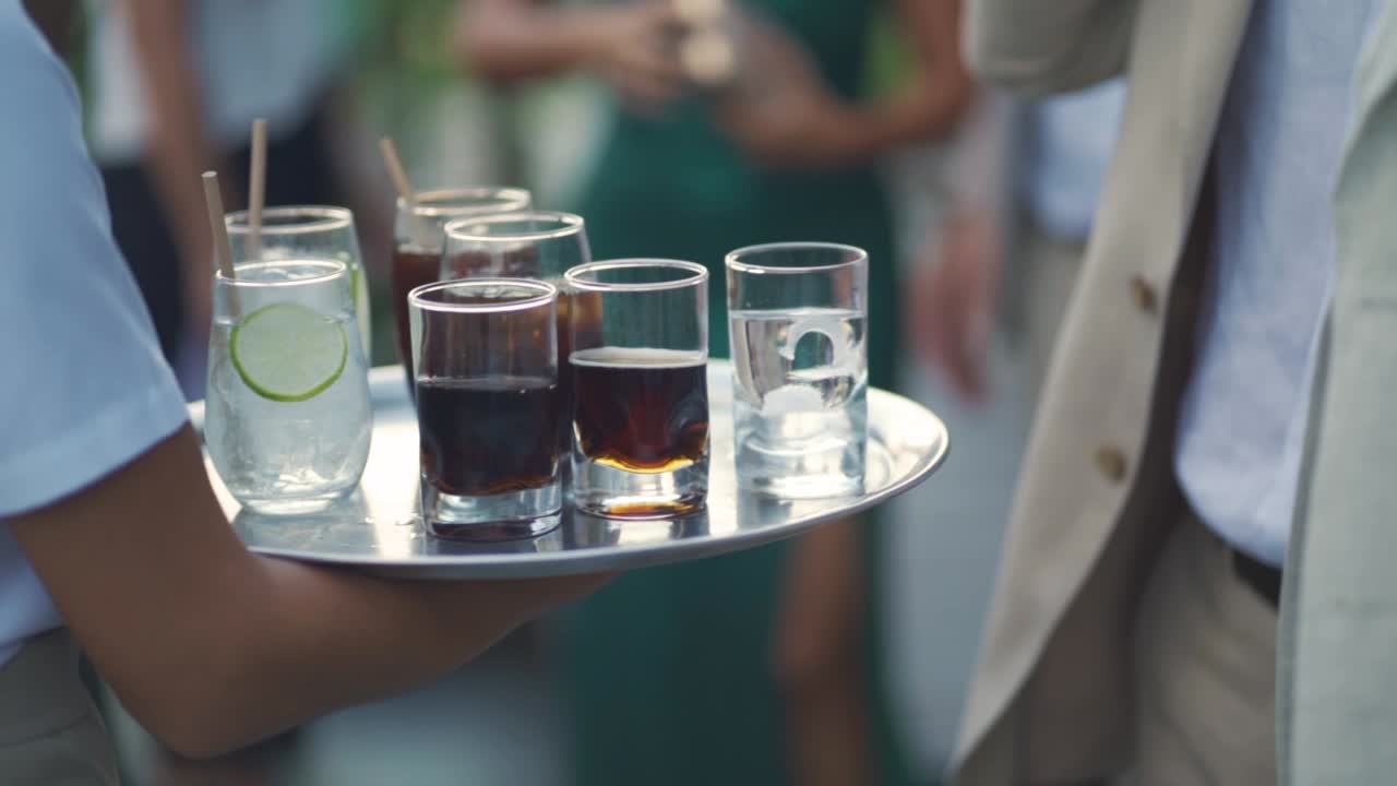 Cameriera che passa un vassoio di bevande tra un gruppo di persone durante una festa di matrimonio