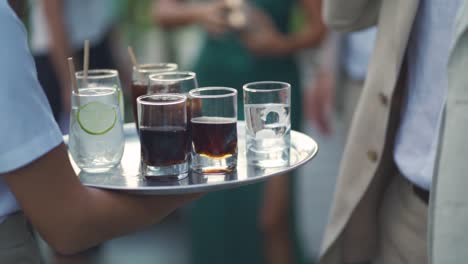 waitress passes a tray of drinks between a group of people during a wedding party