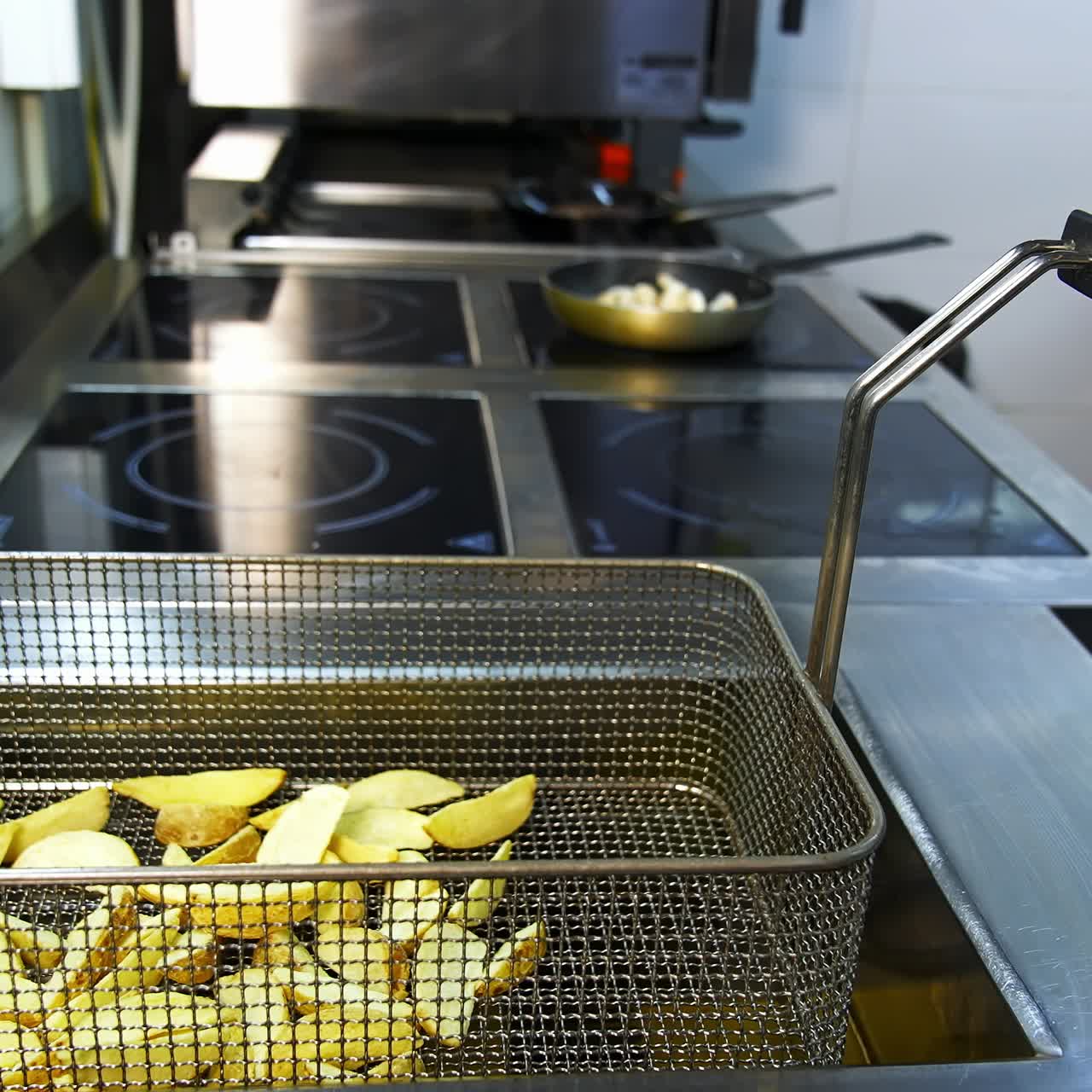 Cooked crispy potato in deep fryer. Golden potato pieces ready to eat. Deep fryer in the restaurant kitchen