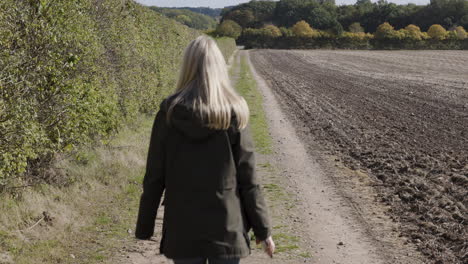 a woman walking on a path through the countryside