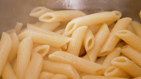 Steaming-hot-fresh-boiled-pasta-in-steel-pot-in-close-up-view