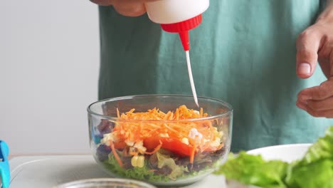 Un-Hombre-Haciendo-Ensalada-Vertiendo-Mayonesa-Sobre-Verduras-Frescas-En-Un-Tazón