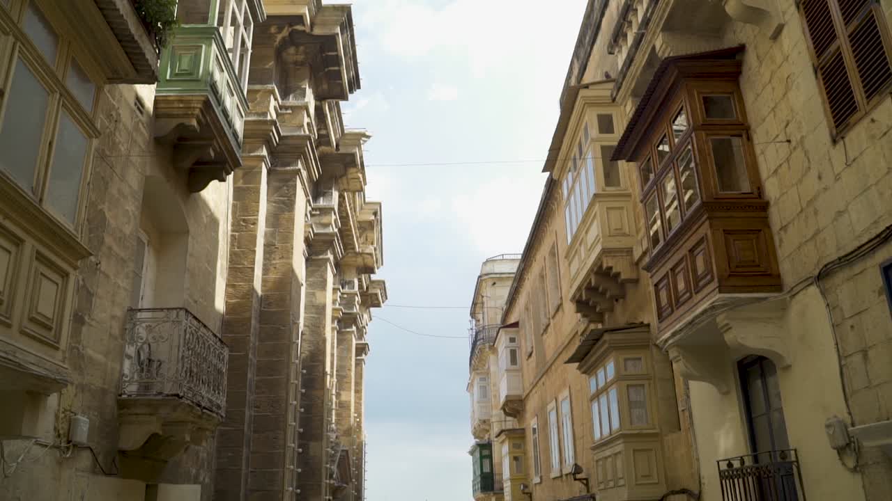 incline hacia abajo desde los balcones en la calle angosta de valletta, la capital de malta