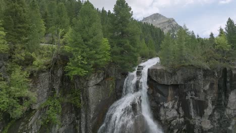 Toma-De-Drones-Que-Muestra-Agua-Cayendo-Por-La-Cascada-Rocosa-En-Las-Montañas-Dolomitas---Inclinada-Hacia-Abajo